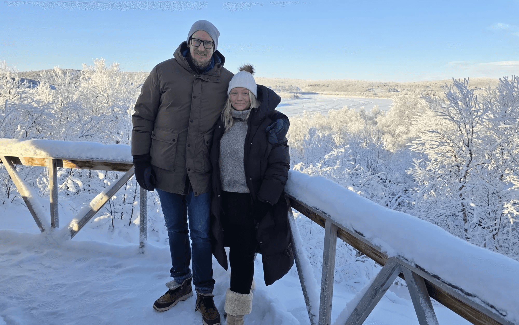 Asle ja Erik aurinkoisena talvipäivänä lumisella terassilla, taustalla huurteiset koivut ja jäätynyt joki
